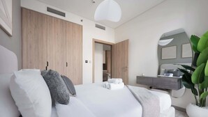 Un dormitorio moderno con una cama grande, un armario de madera y un escritorio con espejo.