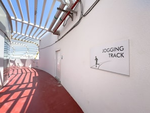En gang med skilt til løbesti, en dør og et loft med rør.