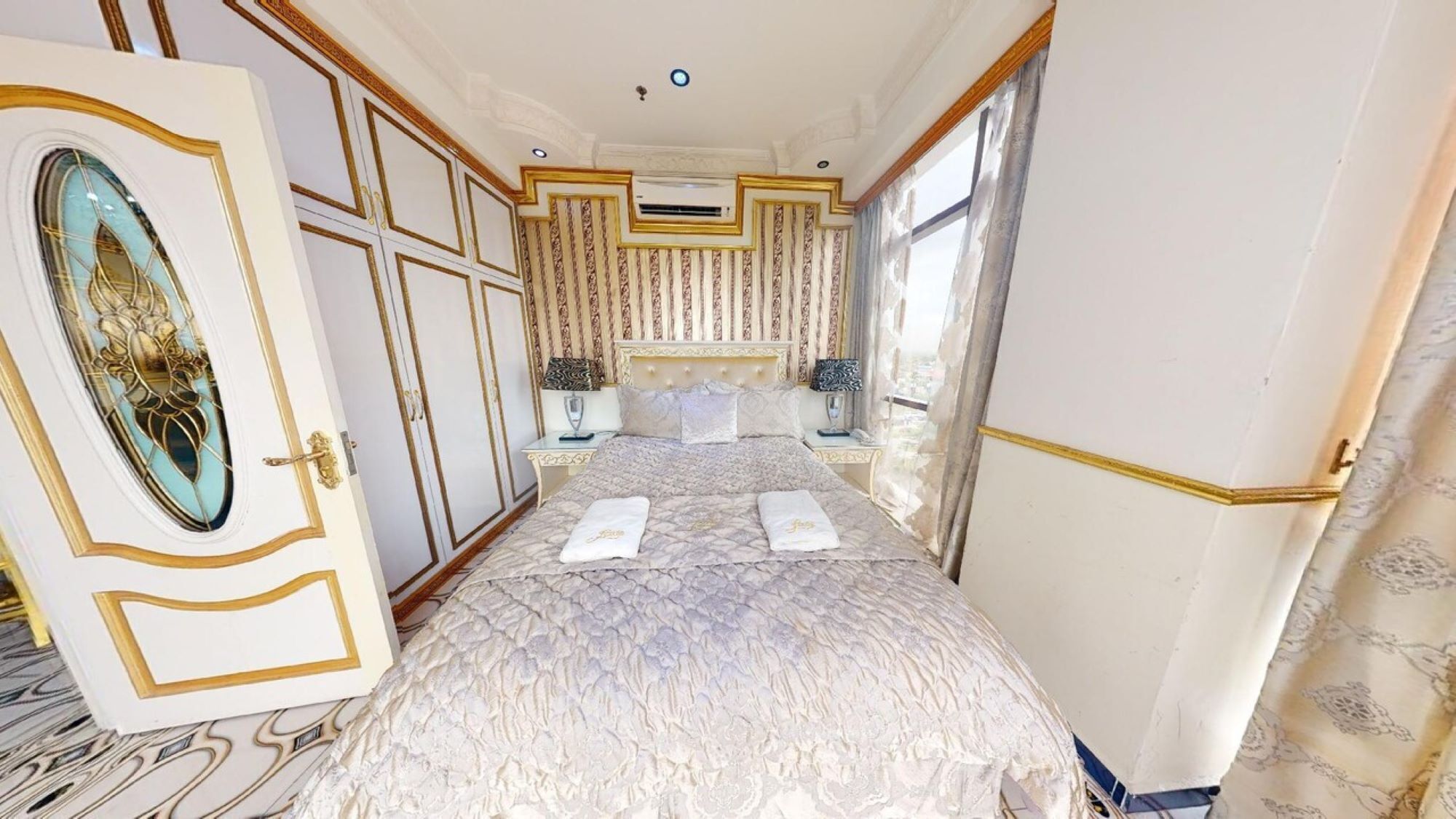 A luxurious bedroom with a large bed, ornate curtains, and a decorative ceiling.