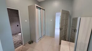 Ένας διάδρομος με πλακάκια στο δάπεδο, μια πόρτα με μεταλλική λαβή και ένας τοίχος με διακόπτη φωτός.