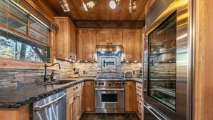 A modern kitchen with wooden cabinets, a stainless steel stove, and a built-in oven. - Classic Cabin in the Pines by Tahoe Getaways - Walk to Lake, Pet-Friendly 3 BR w/ Yard & Hot Tub! (Homewood)