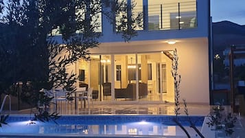 Een modern huis met twee verdiepingen en een glazen deur die leidt naar een eetruimte.