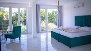 Habitación de hotel con una cama grande, una silla y vistas a zonas verdes por las ventanas.