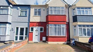 A row of terraced houses with distinct front doors and windows, a paved driveway, and a clear sky. - 6 en-suite Rooms all king beds  (Ilford)