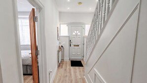 A hallway with a wooden floor, white walls, and a white door at the end. - 6 en-suite Rooms all king beds  (Ilford)