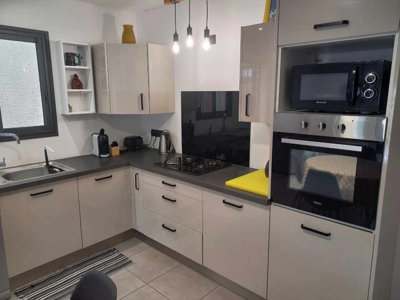 Eine moderne Küche mit weißen Schränken, einem Gasherd, einer Mikrowelle und einem eingebauten Backofen.
