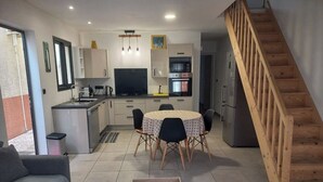 A modern kitchen with a dining area, a sofa, and a staircase. - Comfortable house in a quiet area close to the sea and amenities in a seaside resort. (L'Étang-Salé les bains)