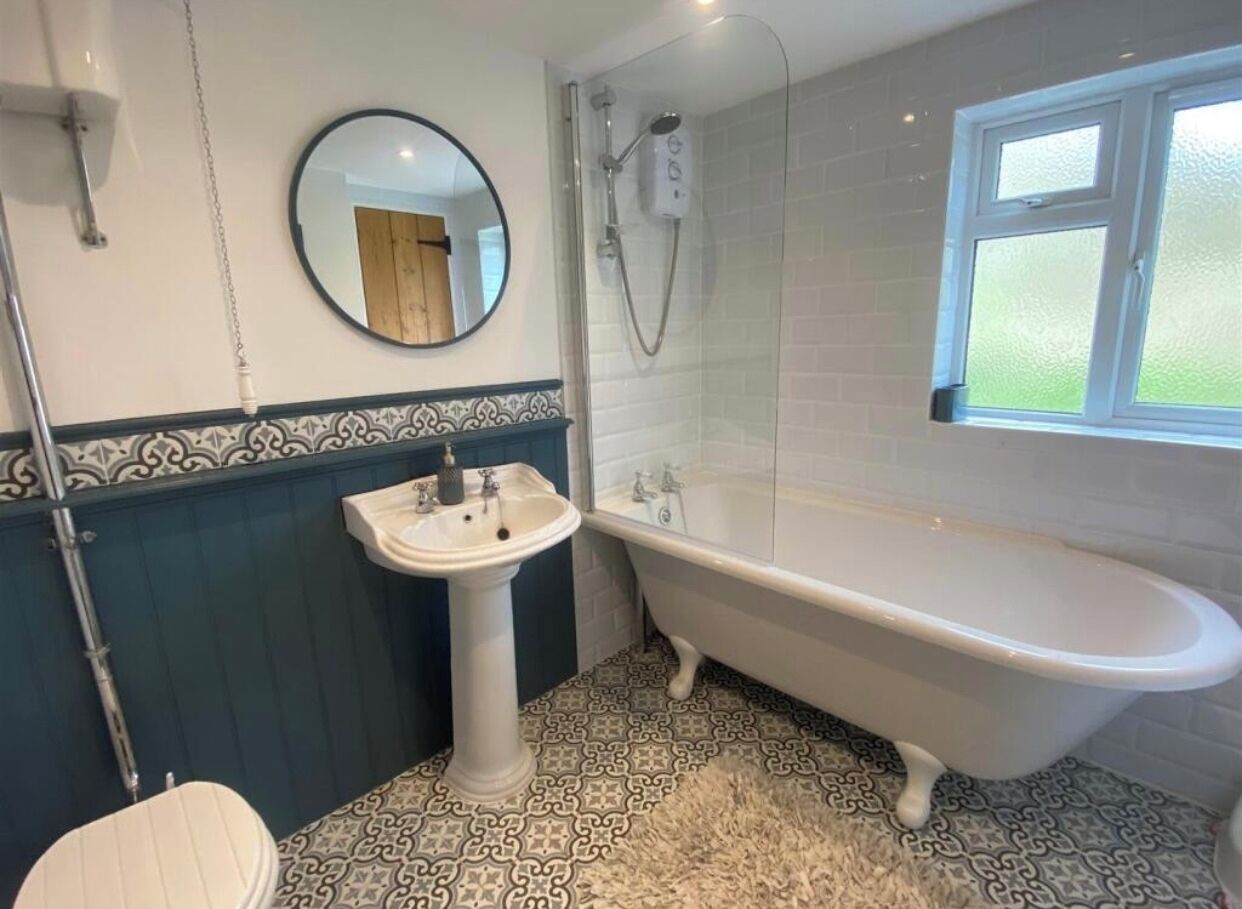 A bathroom with a freestanding bathtub, a pedestal sink, and a shower enclosure.