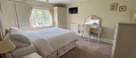 A bedroom with a bed, bedside table, lamp, and a desk with a chair.