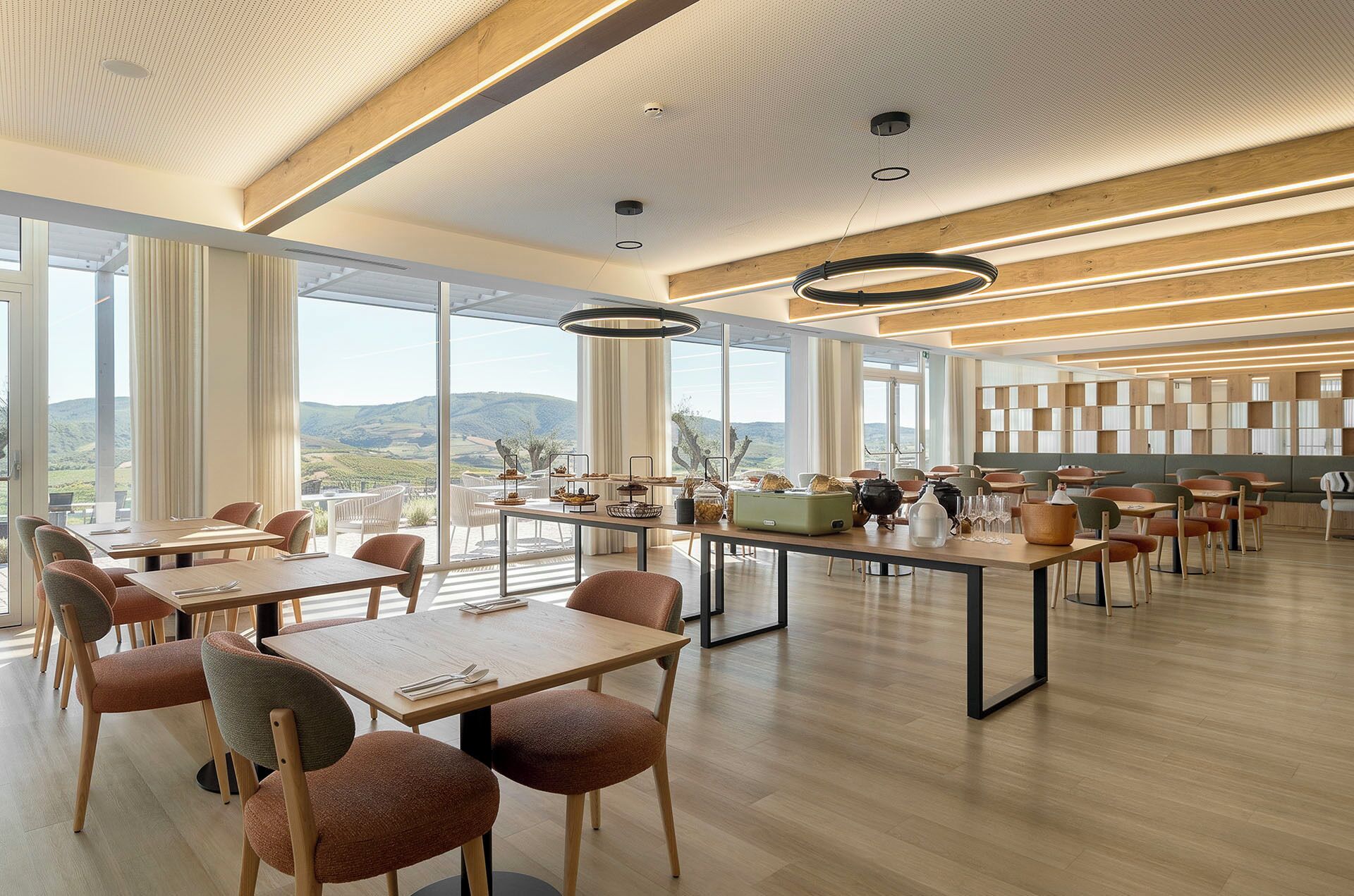 Un vaste espace dédié à la salle à manger, avec de hauts plafonds, de grandes fenêtres et une vue sur l’extérieur.