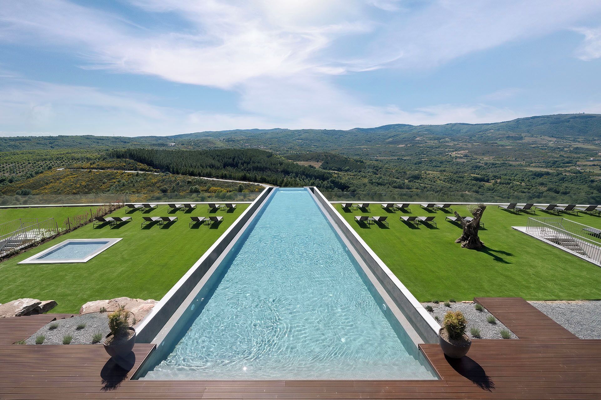 Une longue piscine avec vue sur un paysage verdoyant et des collines à l’horizon.