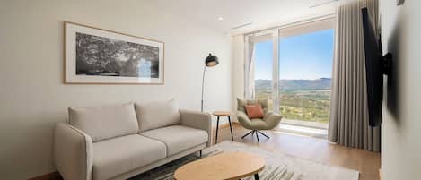 Un salon moderne avec un canapé, une table basse, un lampadaire et une vue sur l’extérieur.