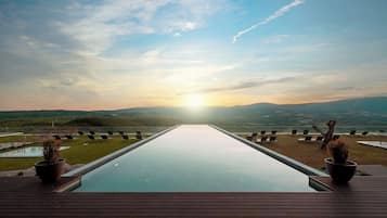 Una piscina techada, una piscina al aire libre, sombrillas