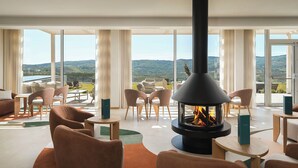 Un interior moderno con chimenea, asientos cómodos y vistas panorámicas al exterior.