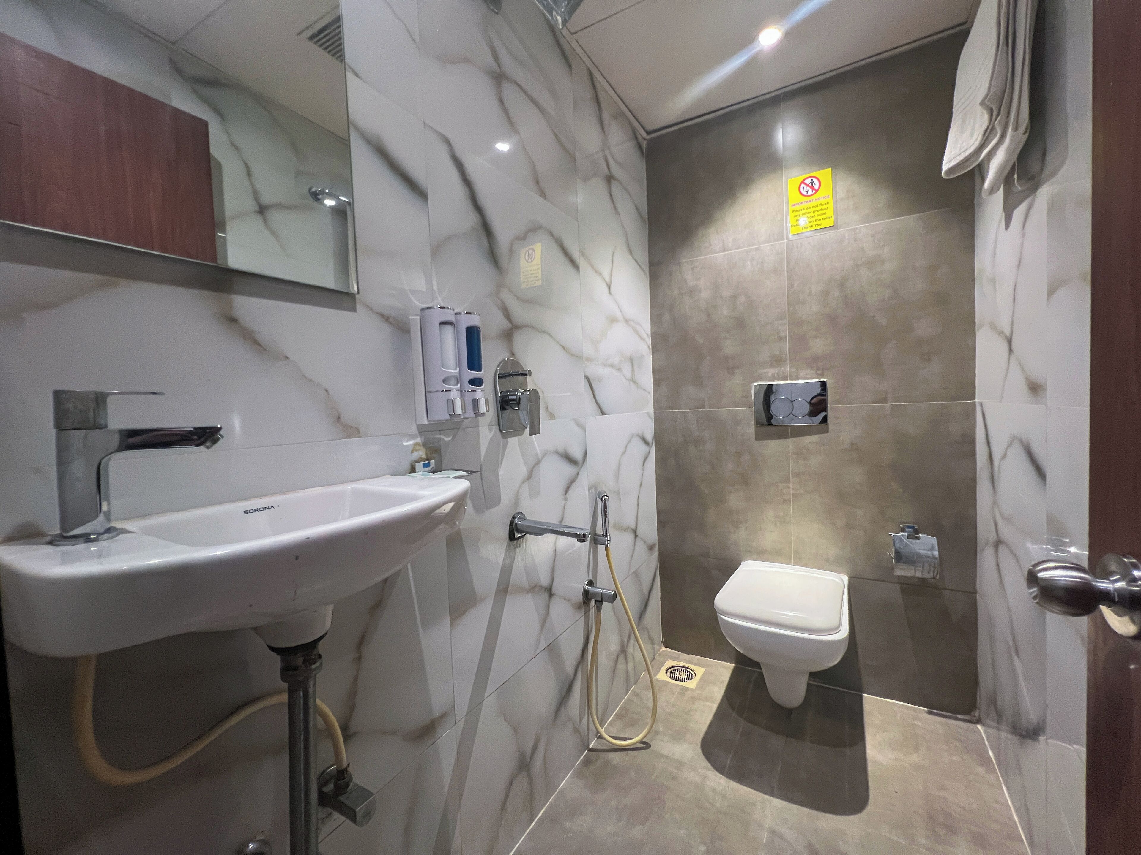 Un baño con lavamanos blanco, un espejo, ducha y retrete.
