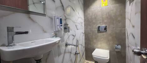 Un baño con lavamanos blanco, un espejo, ducha y retrete.