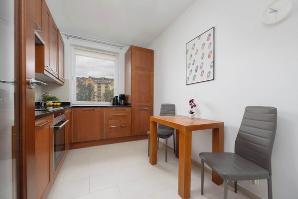 A compact kitchen with wooden cabinets, a built-in oven, and a window with a city view.