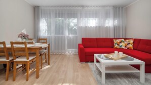 A modern living room with a dining table, red sofa, and a white coffee table. - Intimate Apartment | Two Bedrooms, Work Desk (Wrocław)