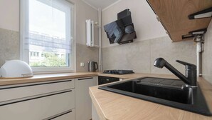 A modern kitchen with a sink, stove, and window. - Intimate Apartment | Two Bedrooms, Work Desk (Wrocław)