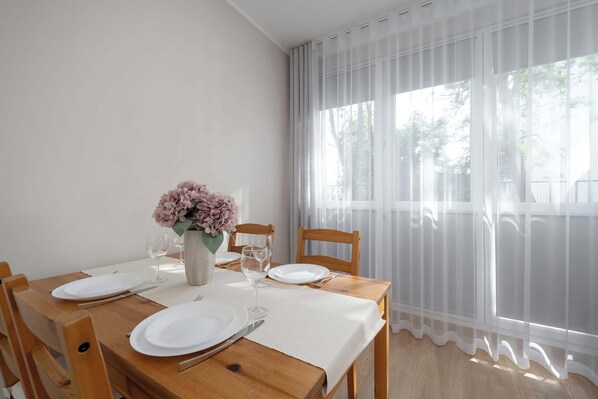 Une table à manger dressée avec des assiettes, des couverts et un vase de fleurs.