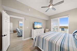 Une chambre à coucher comprenant un lit, un téléviseur, un ventilateur de plafond, une fenêtre avec des stores et une vue sur l’extérieur.