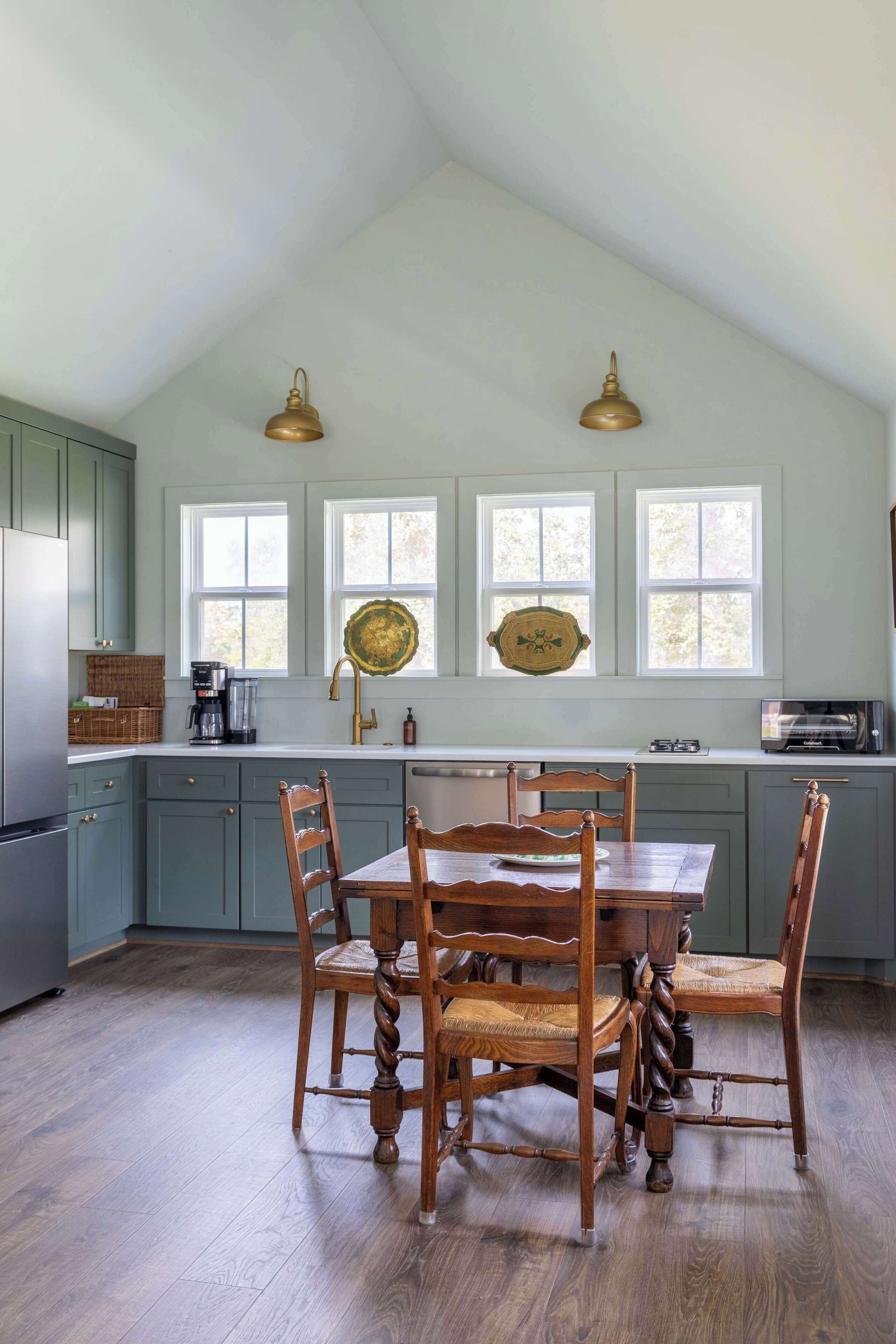 A kitchen with a dining table, chairs, and a window with a decorative plate.