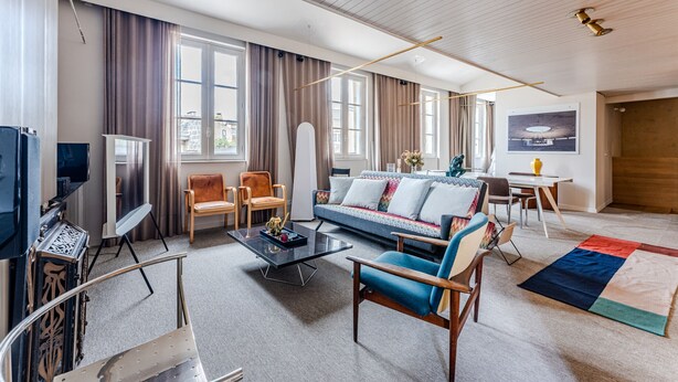 Uma sala de estar moderna com sofá, poltronas, mesa de centro e televisão.