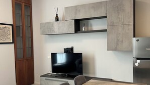 Una sala de estar moderna con comedor, televisión de pantalla plana y muebles empotrados.
