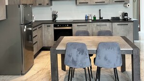 Una cocina moderna con armarios grises, un refrigerador de acero inoxidable, horno empotrado y piso de baldosas de mármol.