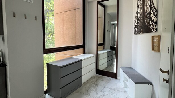 Un baño moderno con un amplio ventanal, un espejo y un banco.