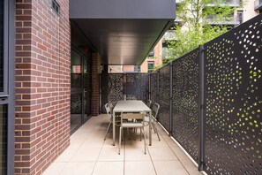 A patio area with a table and chairs, enclosed by a brick wall and a decorative fence. - Calm and Cozy Corner (London)