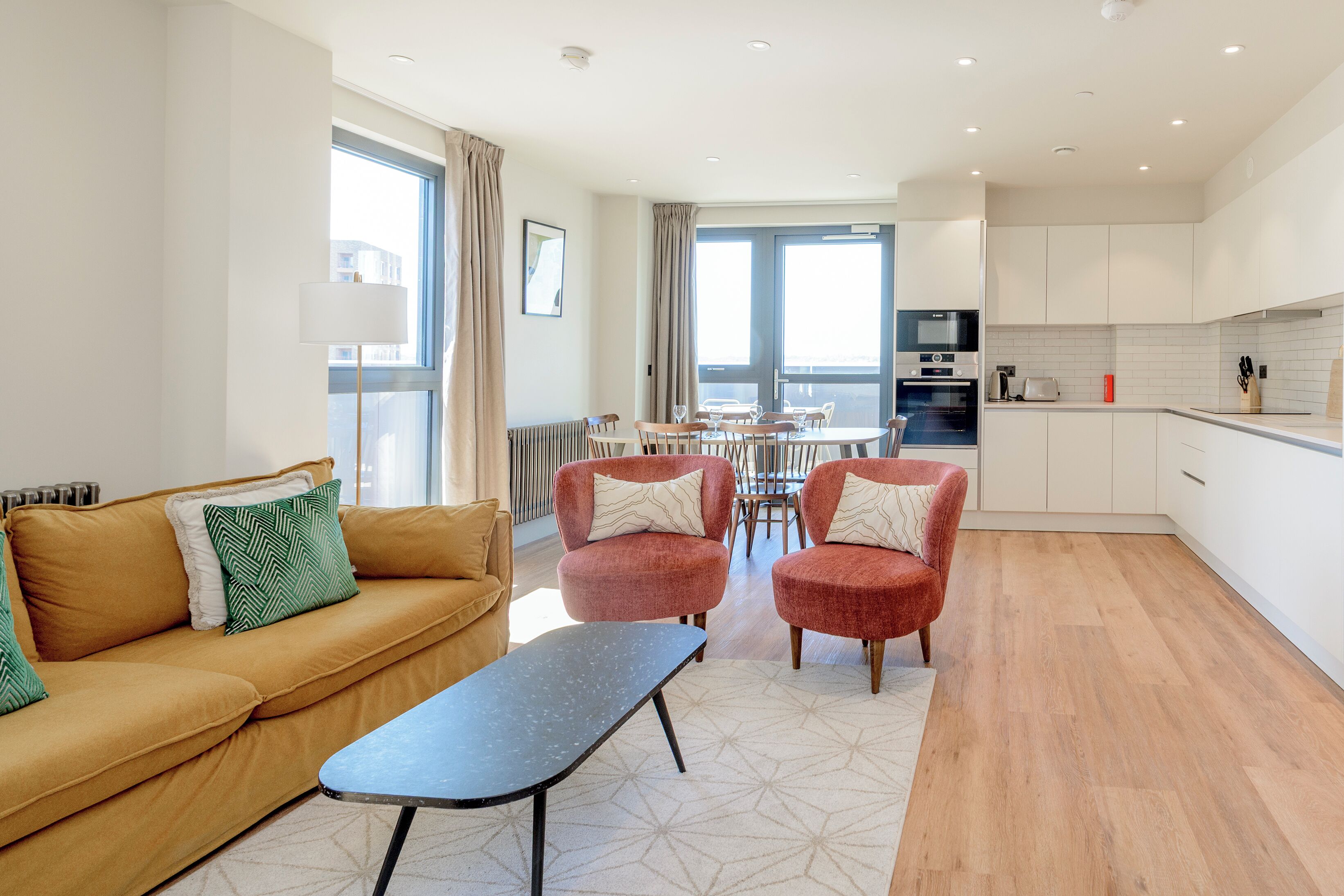Un salon moderne avec un canapé, des fauteuils, une table basse et une vue sur l’espace repas.