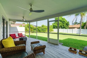 A covered patio with wicker furniture, a ceiling fan, and a view of a green lawn and trees. - Game, Shop & Beach-hop: Family Home in Cape Coral (Cape Coral)