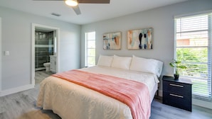 A bedroom with a bed, a ceiling fan, a nightstand, and artwork on the wall. - Game, Shop & Beach-hop: Family Home in Cape Coral (Cape Coral)