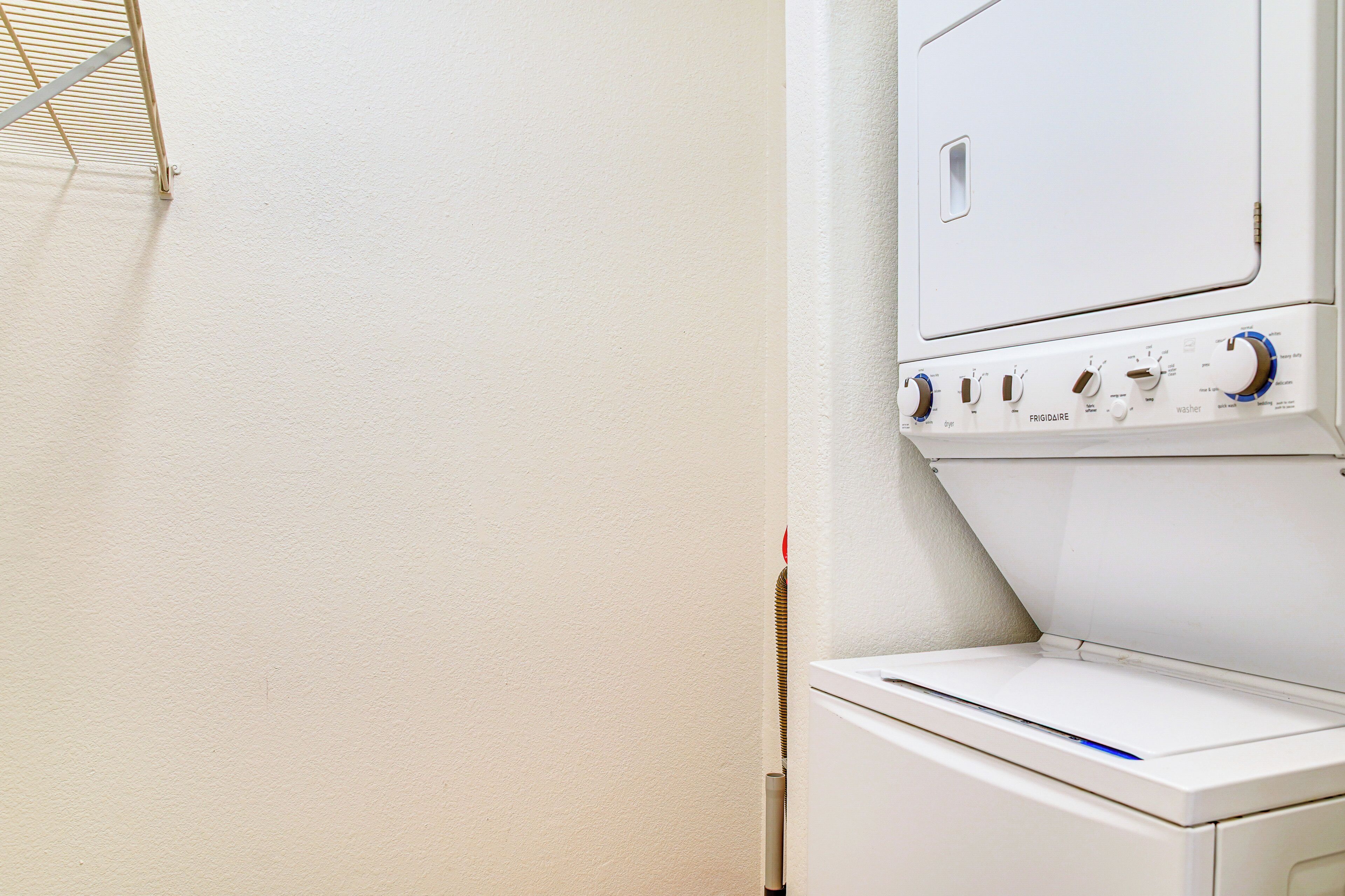A front view of a white washing machine with control knobs and a dryer below it.