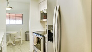 A kitchen with a refrigerator, oven, and microwave. There is a window with blinds, a chair, and a table. - Unwind Poolside! Condo 1 Mi to South Mountain Park (Phoenix)