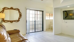 A spacious living room with a brown leather sofa, a large mirror, and a sliding glass door leading to a balcony. - Unwind Poolside! Condo 1 Mi to South Mountain Park (Phoenix)