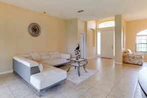 A living room with a sectional sofa, a small table with a decorative item, and a patterned rug.