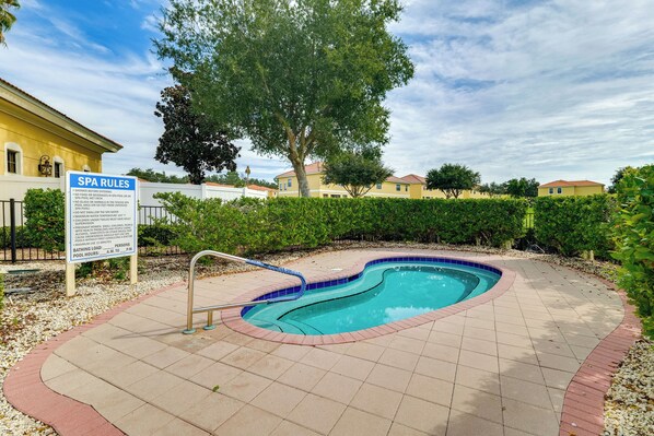 A swimming pool with a sign listing spa rules and pool hours.
