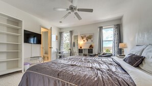A bedroom with a large bed, a ceiling fan, a TV mounted on the wall, and a window with curtains. - 10 Mi to Disney World: Townhome w/ Community Pool! (Kissimmee)