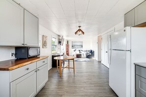 A kitchen with white cabinets, a wooden countertop, a microwave, a dining table, and a refrigerator. - Walk to Beach & Harbor: Spacious Westport Apt! (Westport)