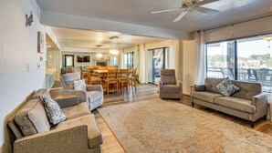 A spacious living room with a large rug, two sofas, a coffee table, and a ceiling fan.
