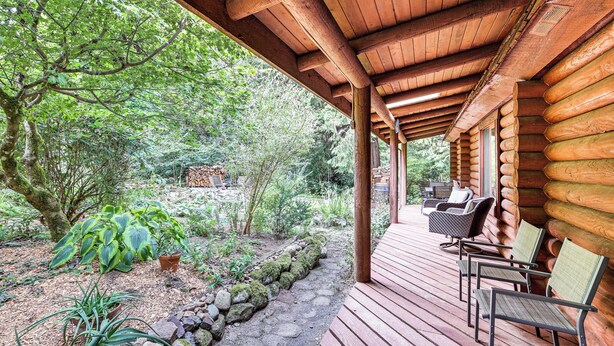 Eine Holzhütte mit Veranda, Sitzgelegenheiten im Freien und Blumentöpfen.