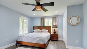 A bedroom with a wooden bed, a ceiling fan, a nightstand, and a wall-mounted mirror. - 12 Mi to Downtown Winston-salem: Apt w/ Balcony! (Winston-Salem)