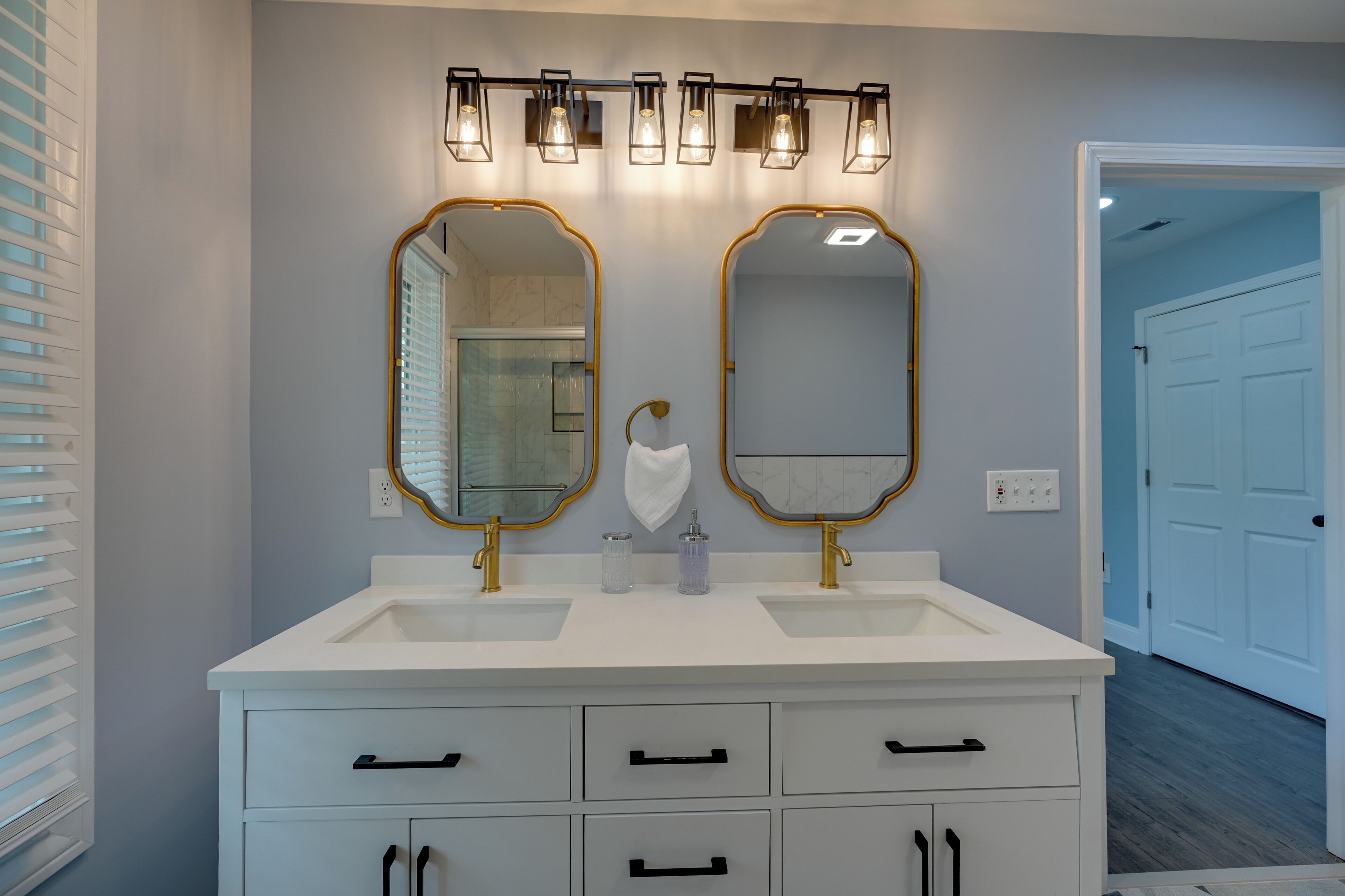 Une salle de bain avec deux lavabos, un meuble-lavabo avec des tiroirs et un miroir avec un cadre doré.