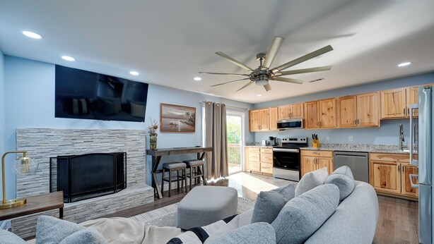 A modern living room with a large flat-screen TV, a fireplace, and a ceiling fan. - 12 Mi to Downtown Winston-salem: Apt w/ Balcony! (Winston-Salem)