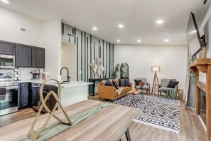 A modern kitchen with dark cabinets, a wooden dining table, and a patterned rug. - Walk to Table Rock Lake: Updated Cabin w/ Deck! (Kimberling City)