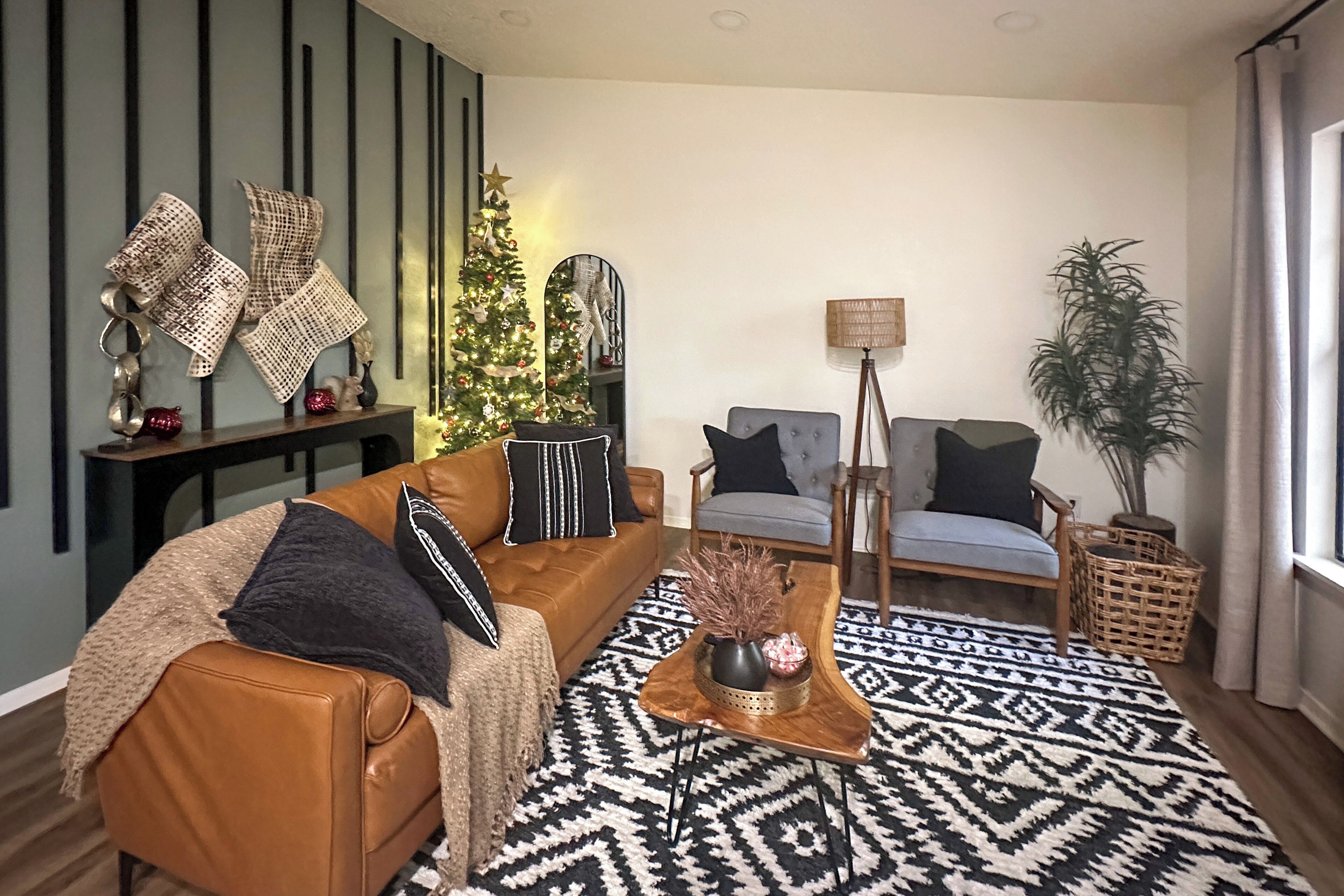 Una sala de estar con un sofá de cuero marrón, un tapete estampado, un árbol de Navidad y una lámpara.