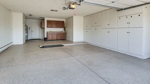 A garage with a concrete floor, white cabinets, and a ceiling light fixture. - Golf, Swim & Grill: Snowbirds Escape in Sun Lakes (Chandler)