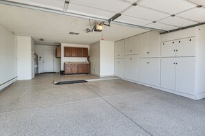 Eine Garage mit Betonboden, weißen Schränken und einer Deckenleuchte.